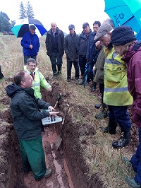 Gavin Elrick & Paul Hargreaves, soil specialists in a soil pit talking to a group of farmers