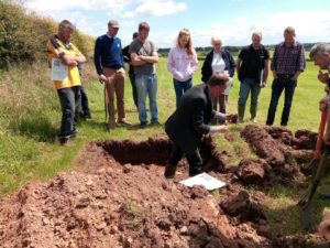 Paul Hargreaves explaining soil structure whilst in a soil pit on a sunny day with a group of farmers watching