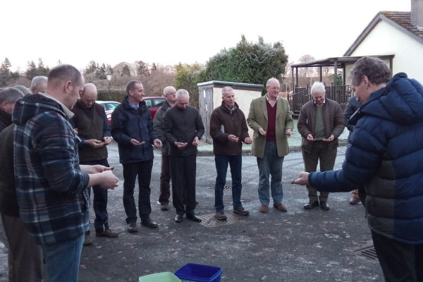 A group of people standing outside looking at handfuls of soil as part of the integrated crop management meeting in Perth in December