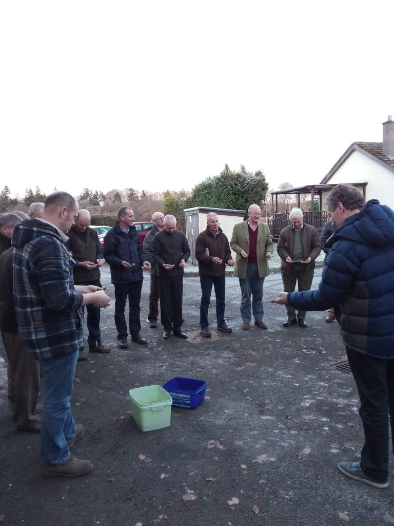 A group of people standing outside looking at handfuls of soil as part of the integrated crop management meeting in Perth in December