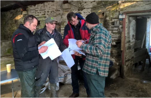 Farmers at the Knockglass Soil & Nutrient Network meeting at Knockglass Farm, Caithness. They are all looking through handouts from the event