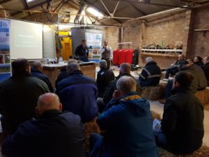 ICM Laurenckirk - photo of farmers at a meeting, sitting on straw bales inside a shed