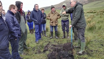 Kintyre SNN photo shows a group of people in a field looking at drainage in soil