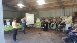Upland habitats event on Jura - a group of people inside a shed listening to a presentation being given with a powerpoint presentation on view in the background