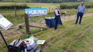Farming & Water Scotland stand in a grassland field with a representative discussing Springback fencing, with a demonstration section of it in the background