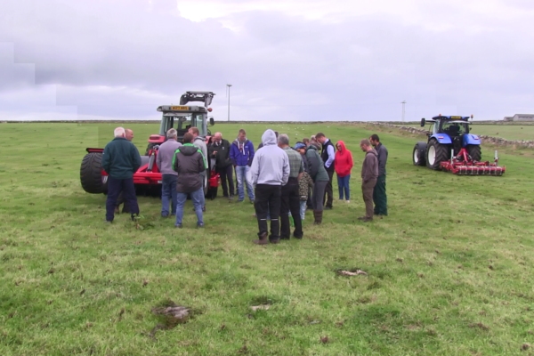 Farmers attending the Orkney SNN meeting standing in a grassland field with soil compaction remediation machinery