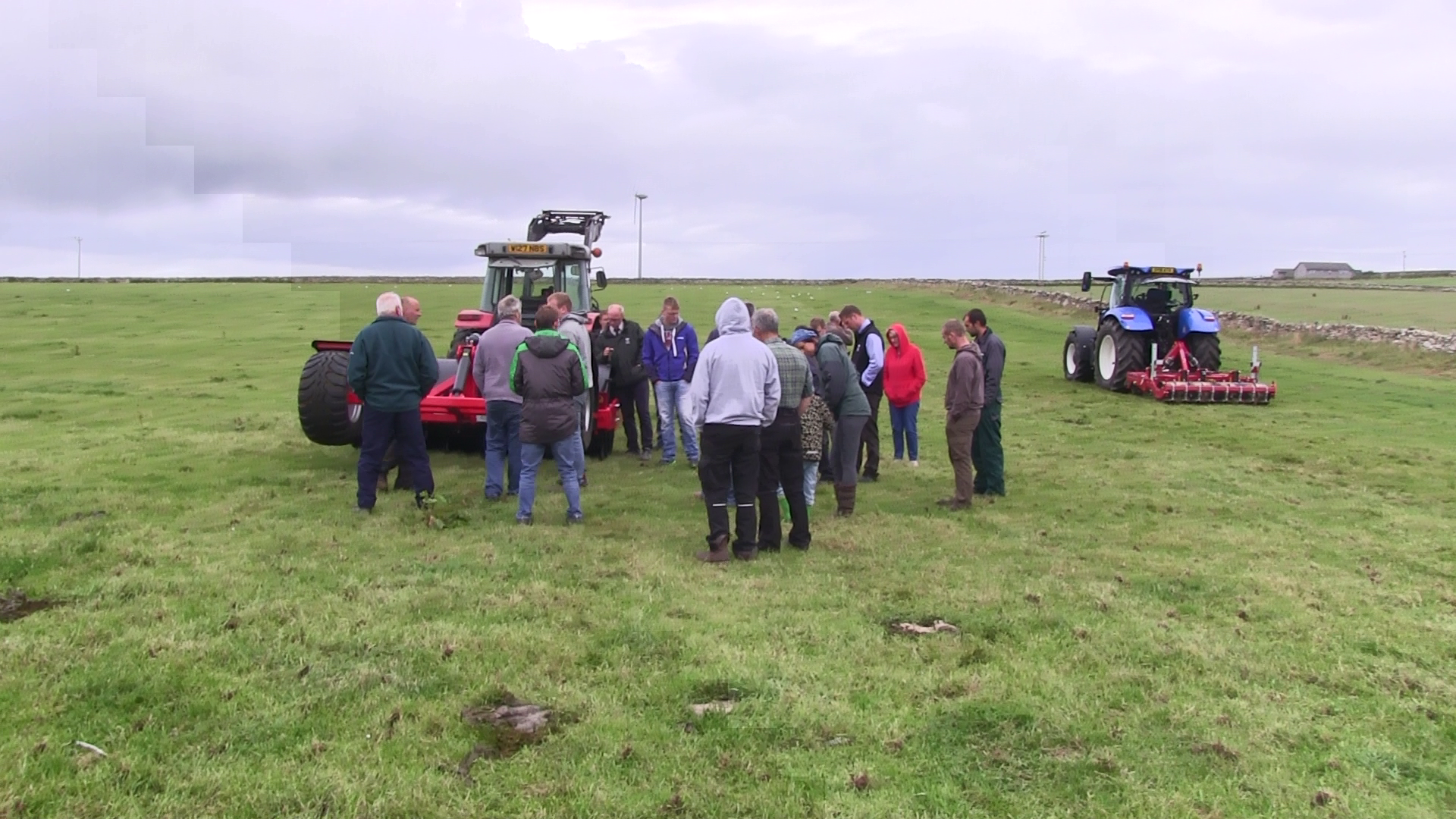 Farmers attending the Orkney SNN meeting standing in a grassland field with soil compaction remediation machinery