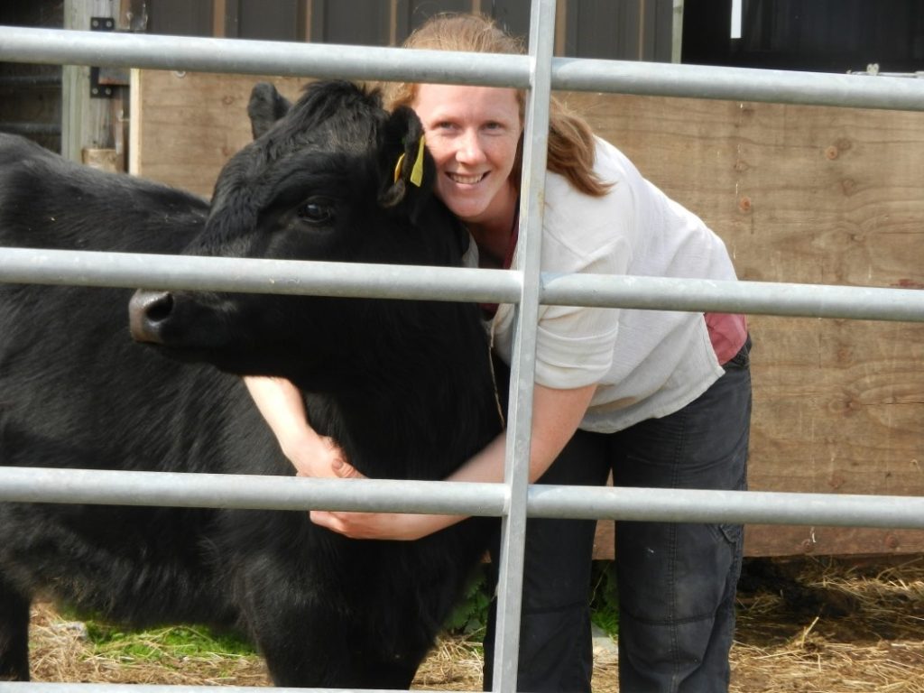 Smiling woman hugging black cow
