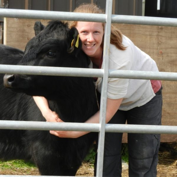 Smiling woman hugging black cow