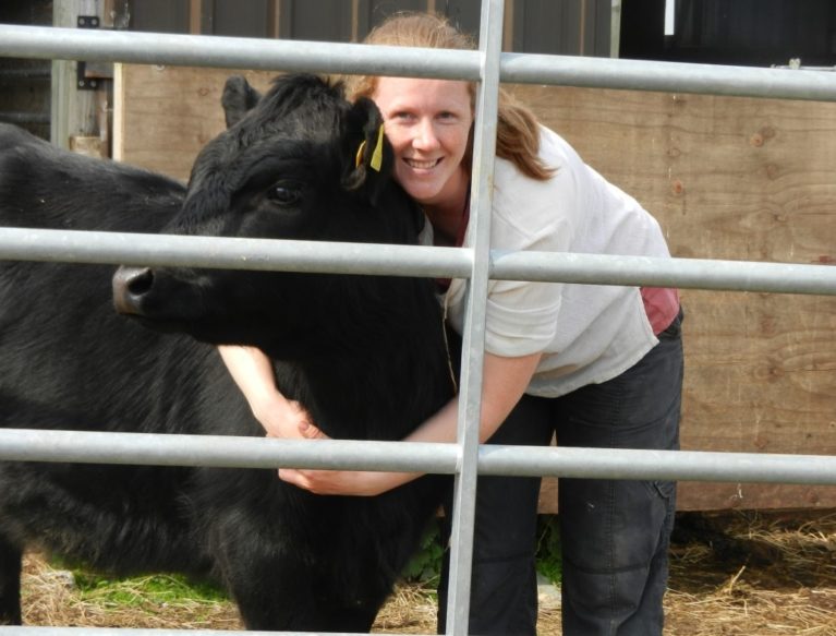 Smiling woman hugging black cow