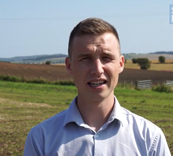Consultant stood in a field, looking at the camera.