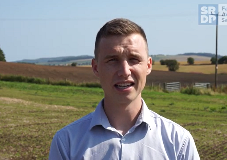 Consultant stood in a field, looking at the camera.