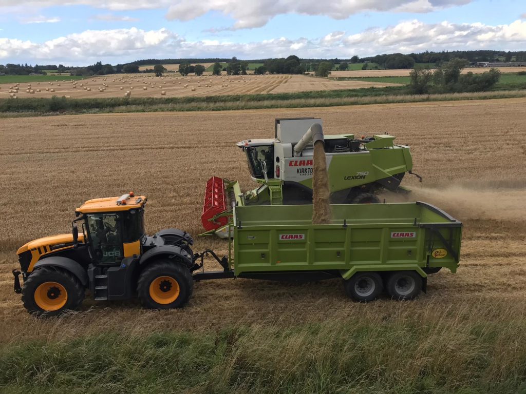 tractor, trailer and combine harvester gathering crop