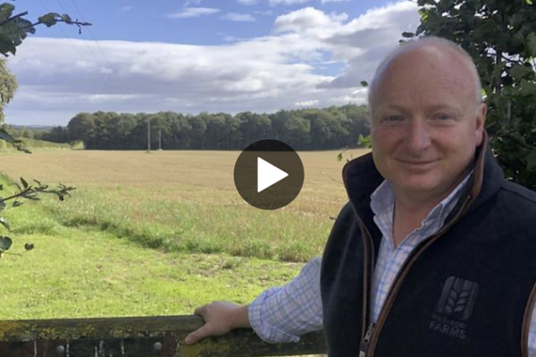 Colin McGregor standing at a gate in front of a field.