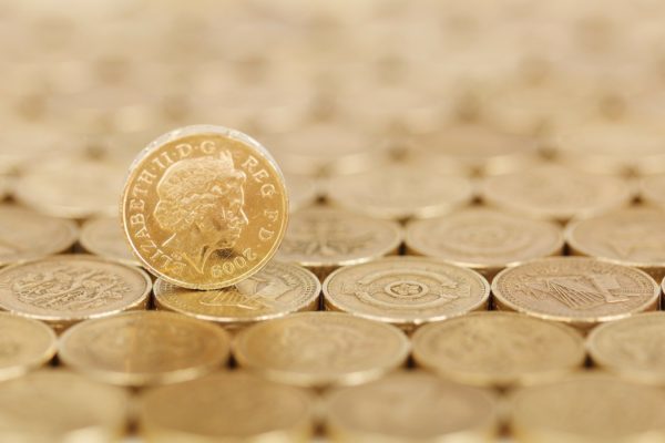 one british pound coin stood up on a surface made from other coins