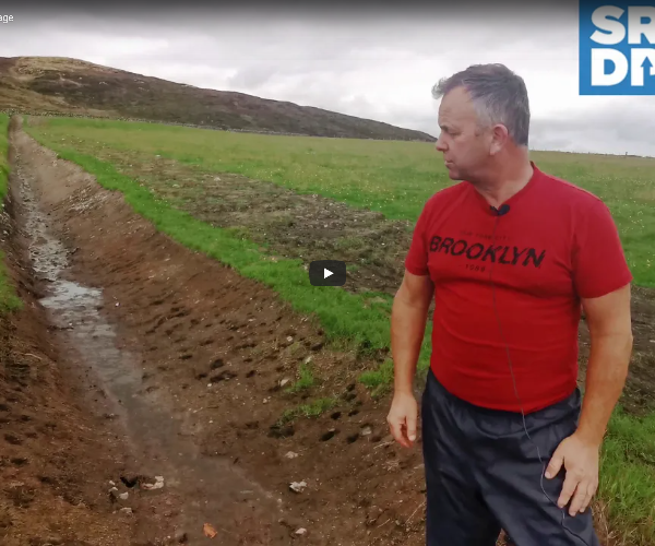A farmer stood at the bottom of a newly dug drainage ditch