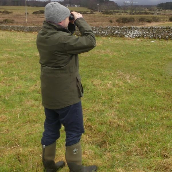 Farm Advisory Service - man standing in a field looking through binoculars