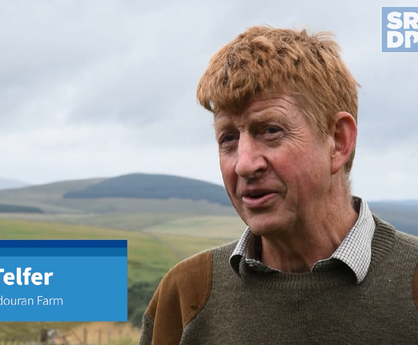 Doug Telfer, a farmer who has farmed at Glendouran Farm for all of his life, standing in a grassland field and talking to someone who is slightly behind the camera.