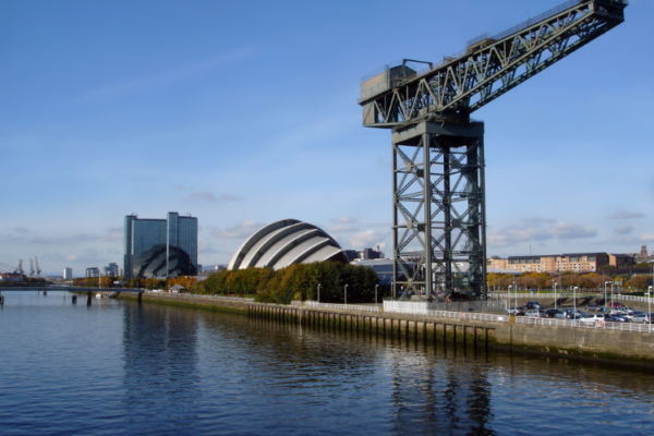 A view along the River Clyde in Glasgow with the iconic crane in the foreground and the SECC building behind it.