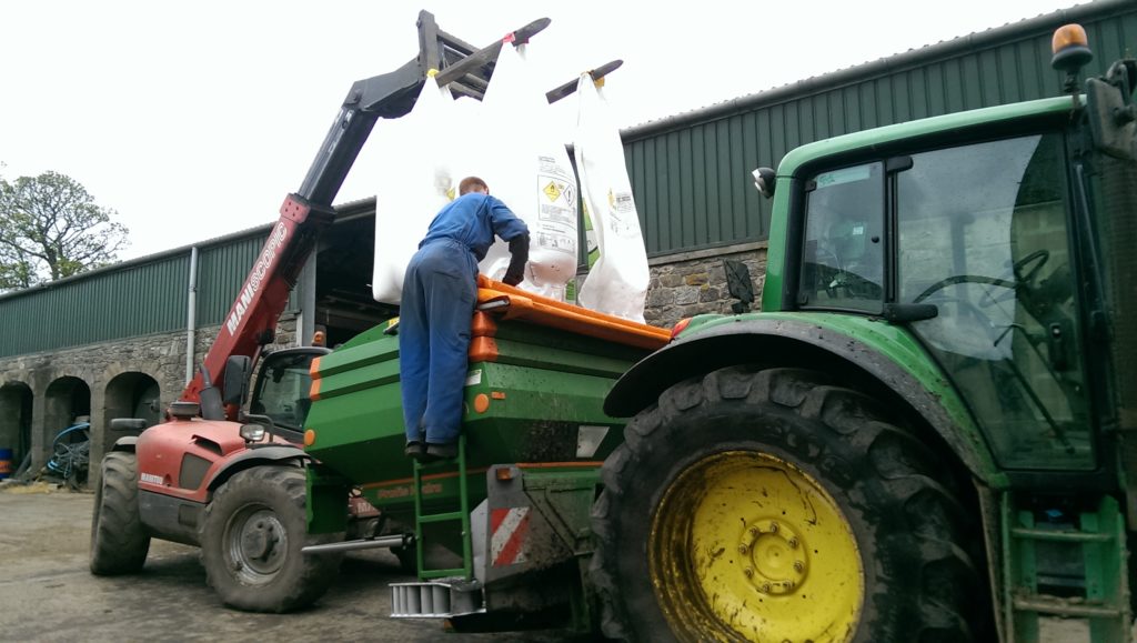 Farmer loading fertiliser into a manure spreader