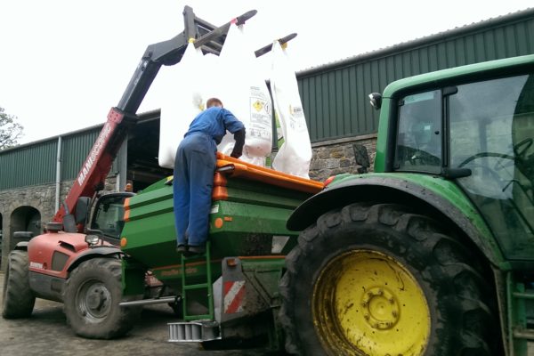 Farmer loading fertiliser into a manure spreader