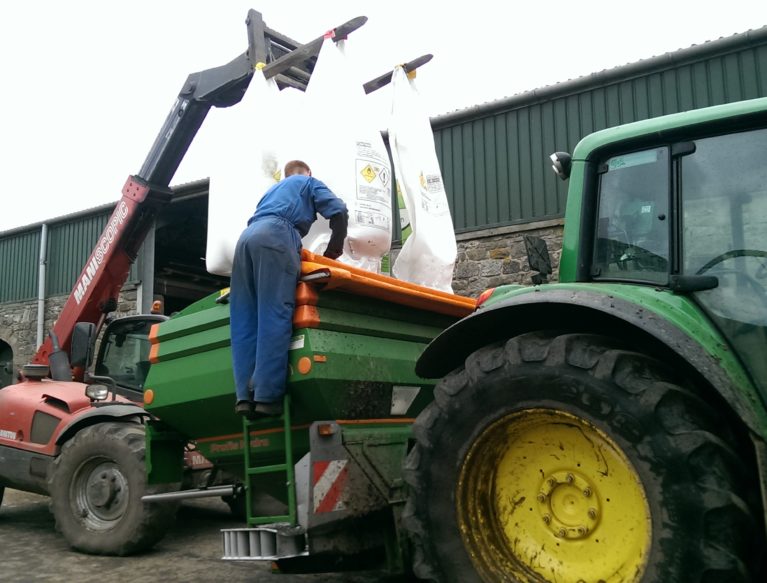 Farmer loading fertiliser into a manure spreader
