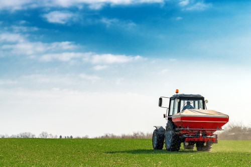 tractor spreading fertiliser on wheat crop