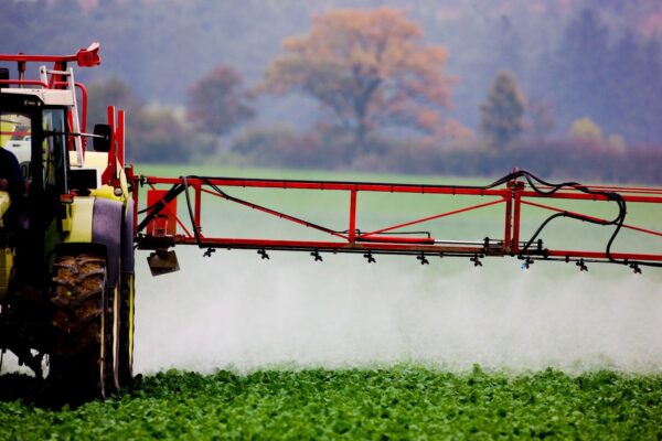 A tractor spraying a field with a sprayer.