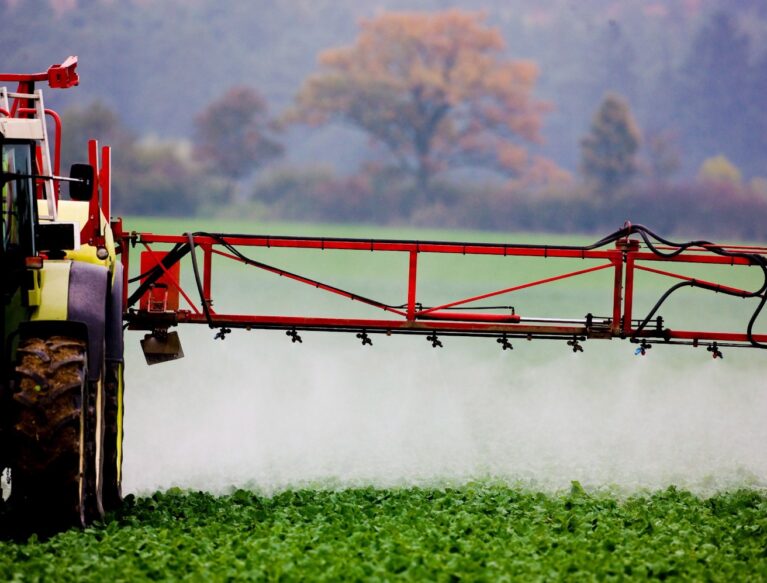 A tractor spraying a field with a sprayer.