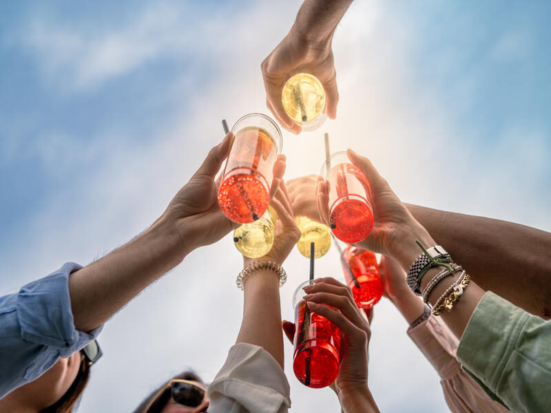 women's arms holding drinks together in a cheers motion