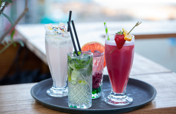 Colourful drinks and a milkshake on a tray